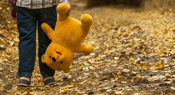 Kind mit Teddy in der Hand im Freien