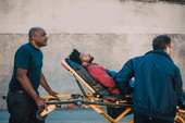 Bewusstloser Mann wird von zwei Rettungssanitätern abtransportiert