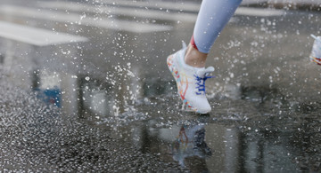 Foto von cottonbro von Pexels: Frau läuft bei Regen Ausschnitt Bein