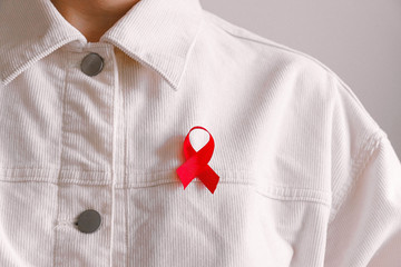 Rote Schleife für Aids an weißer Jeansjacke