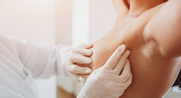 Arzt tastet Frauenbrust ab zur Brustkrebsvorsorge