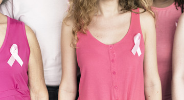 Frauengruppe mit rosa Schleife an T-Shirt als internationales Symbol, mit dem auf die Problematik der Brustkrebserkrankung hingewiesen wird.  