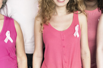 Frauengruppe mit rosa Schleife an T-Shirt als internationales Symbol, mit dem auf die Problematik der Brustkrebserkrankung hingewiesen wird.  