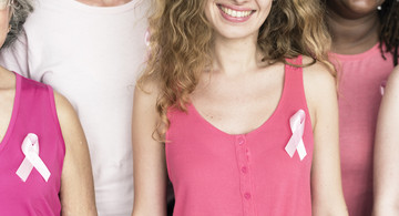 Frauengruppe mit rosa Schleife an T-Shirt als internationales Symbol, mit dem auf die Problematik der Brustkrebserkrankung hingewiesen wird.  